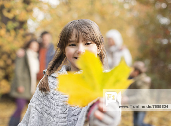 Girl holding autumn leaf in park