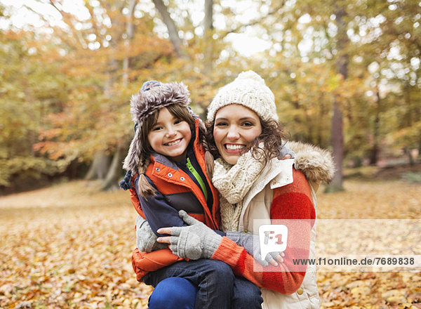 Mother and daughter smiling in autumn leaves