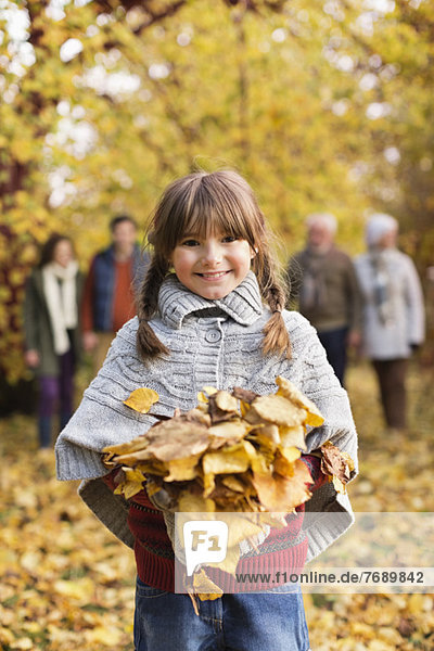 Lächelndes Mädchen spielt im Herbstlaub