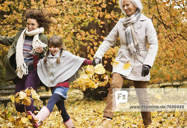 Drei Generationen von Frauen spielen im Herbstlaub