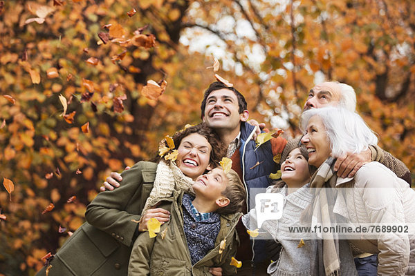 Family playing in autumn leaves in park