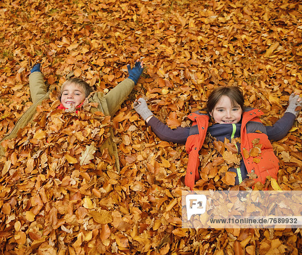Children laying in autumn leaves