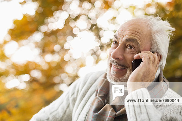 Older man talking on cell phone in park