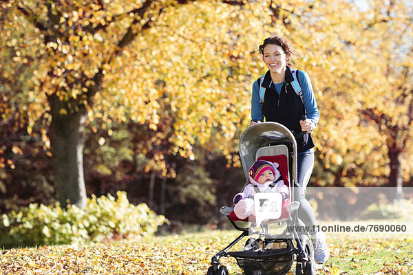Frau beim Laufen mit Kinderwagen im Park