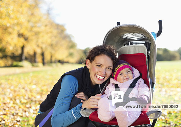 Frau lächelt mit Baby im Kinderwagen