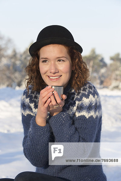 Caucasian woman drinking coffee in snow