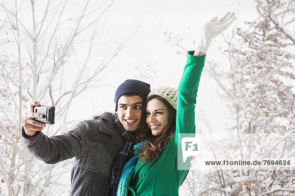 Couple taking pictures together in snow