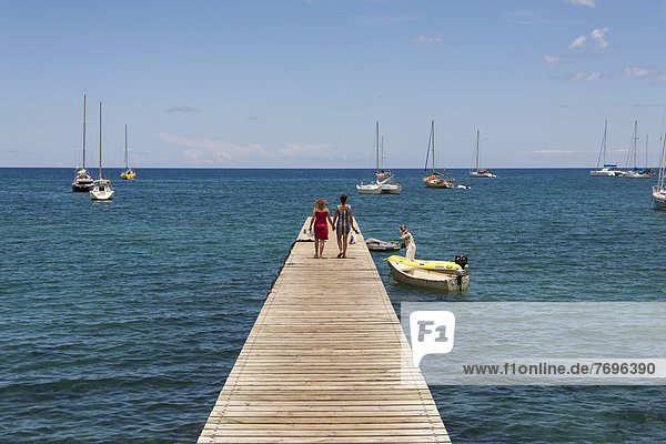 Two people walking on a jetty  Deshaies  Guadeloupe  Lesser Antilles  Caribbean