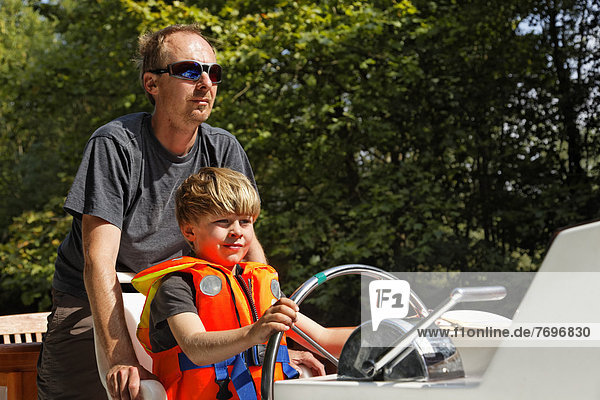 Vater und Sohn am Steuer auf Hausboot  auf dem Canal du Midi bei Bram
