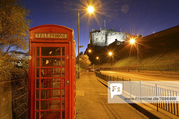 Edinburgh Castle  illuminated at night  old red British phone booth at front
