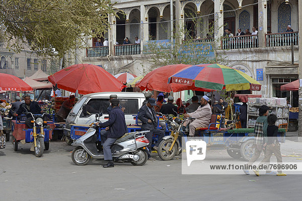 Market stalls with Muslim traders and a tea room on the porch of a mudbrick house  Uyghur Muslim Quarter