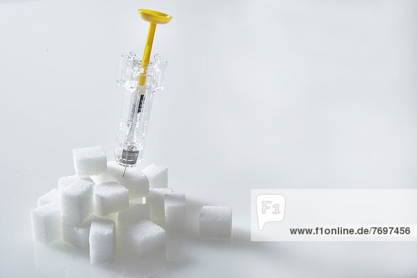 Haufen von Zuckerstücken mit Insulinspritze