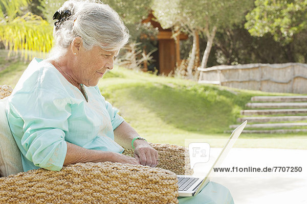 Older woman using laptop outdoors