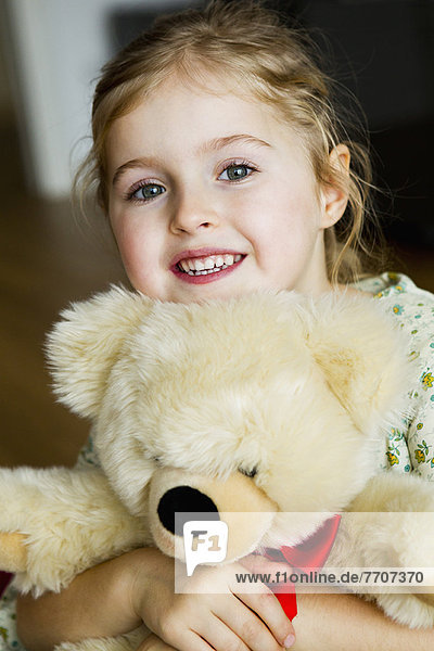 Lächelndes Mädchen umarmt Teddybär