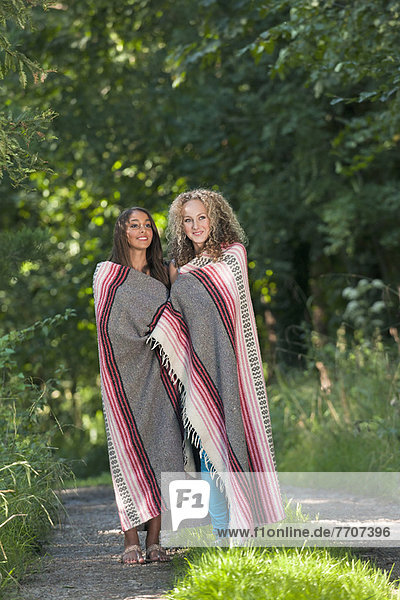 Teenage girls in blanket on rural road