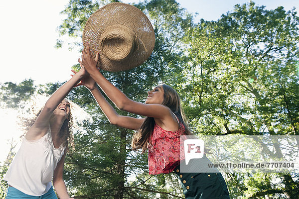 Teenage girls playing with straw hat