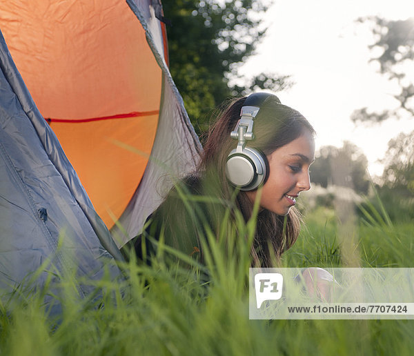Teenage girl in headphones at campsite