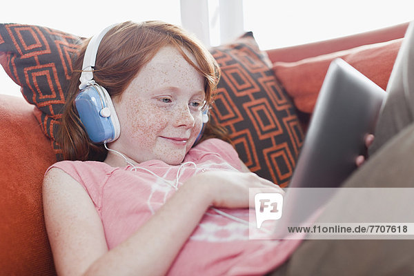 Mädchen in Kopfhörern mit Tablet-Computer
