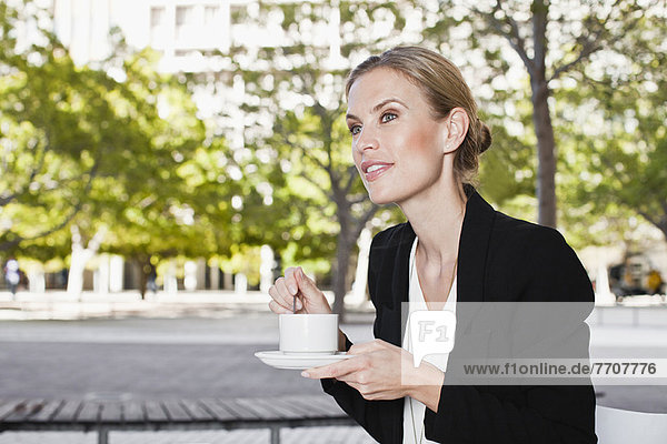 Businesswoman having coffee on city street