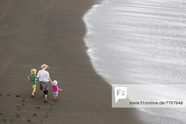 Mutter und Kinder beim Spaziergang am Strand