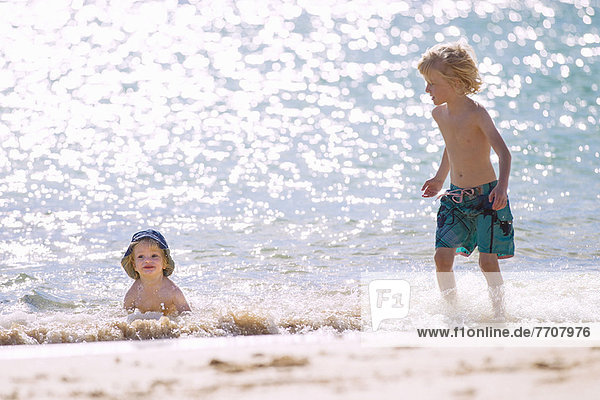 Kinder spielen in Wellen am Strand