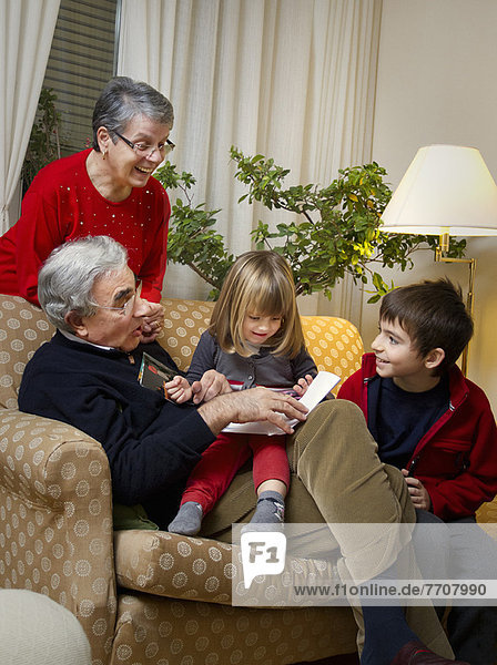Älteres Paar mit Enkelkindern auf dem Sofa