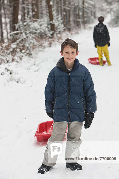 Boy holding sled on snowy slope
