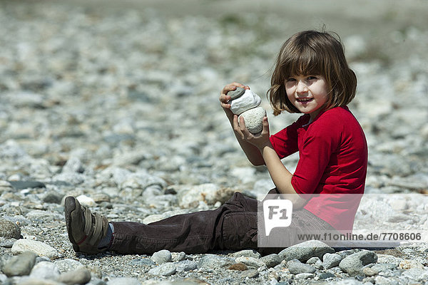 Mädchen spielt mit Steinen am Strand