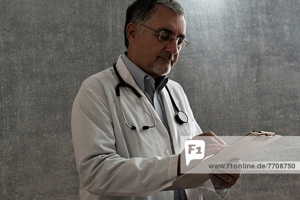 Männlicher Arzt beim Schreiben auf der Karte