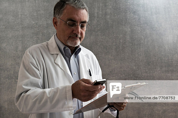 Male doctor with cellphone and clipboard