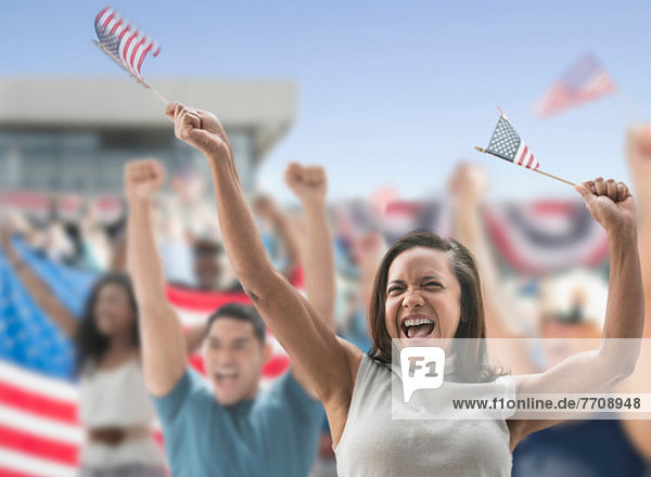 Aufgeregte Frau mit amerikanischen Flaggen bei der Rallye