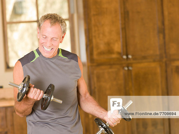 Older man lifting weights at home