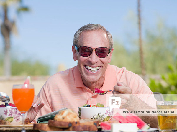 Older man having breakfast outdoors