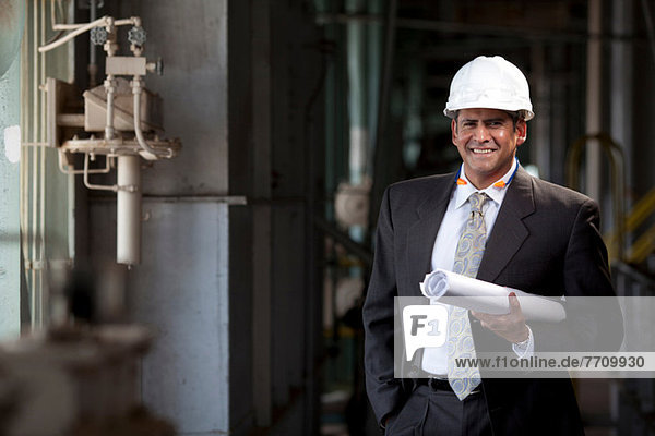 Businessman with blueprints in plant