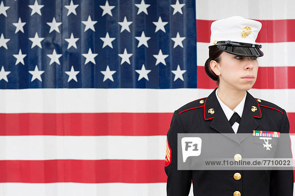 Servicewoman in dress blues by US flag