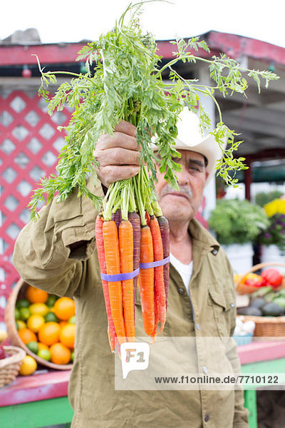 Mann mit Karotten auf dem Bauernmarkt