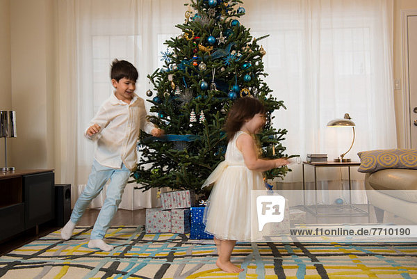 Children playing around Christmas tree