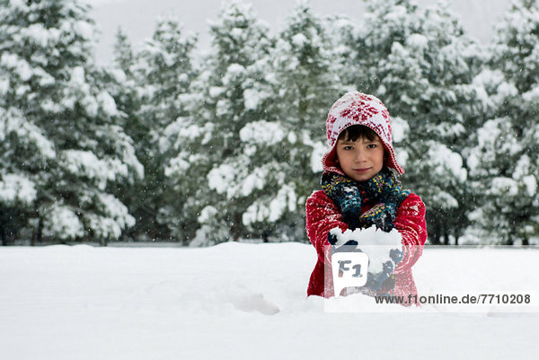 Boy holding snowball outdoors