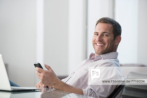 Businessman using cell phone at desk