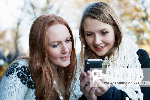 Frauen  die gemeinsam ein Handy benutzen