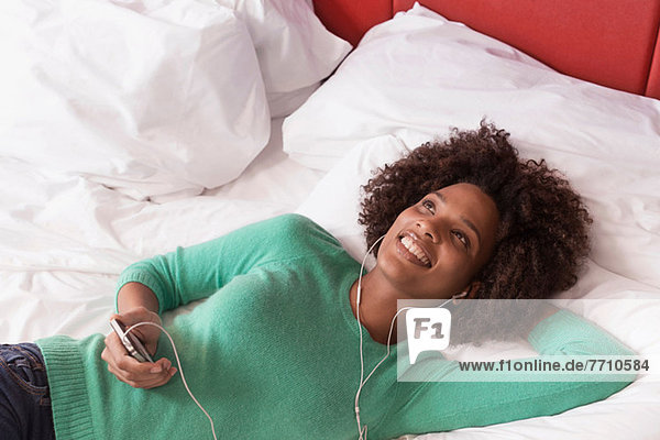 Woman listening to earphones on bed