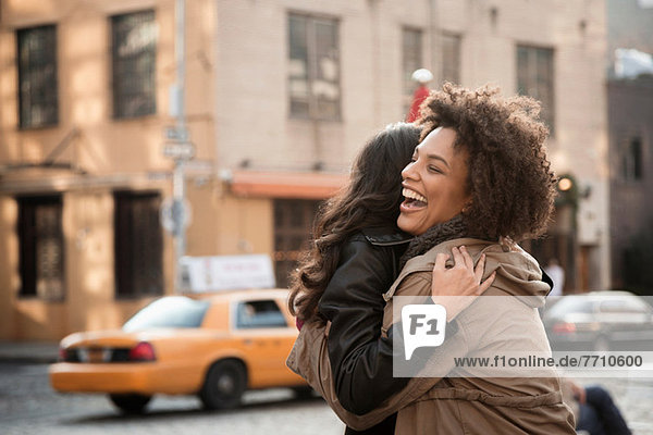 Women hugging on city street