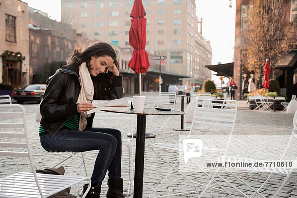 Woman reading at sidewalk cafe