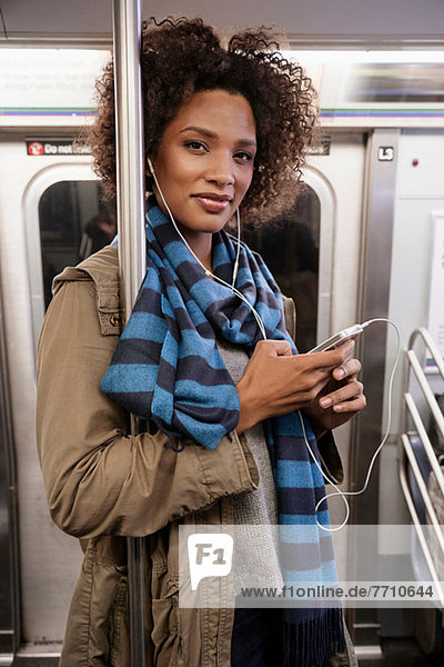 Woman listening to earphones on subway