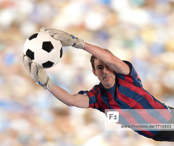 Soccer player catching ball in air