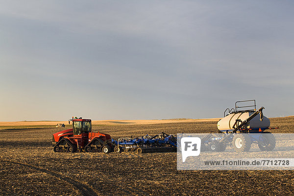 Tractor And Air Seeder In Field With Blue Sky At Sunrise  Alberta  Canada