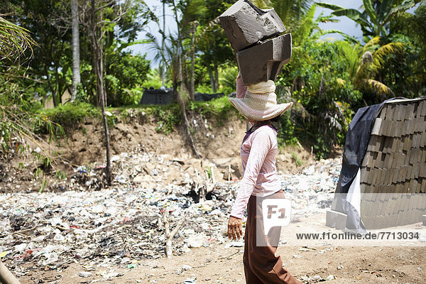 A Woman Carries Heavy Cement Blocks On Her Head  Bali  Indonesia