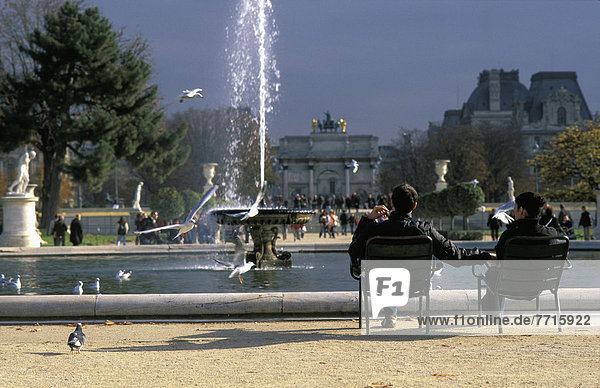 Couple Sitting In Front Of Fountain In Tuileries Gardens