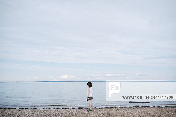 Young girl standing on a beach by the water Saint-simeon quebec canada