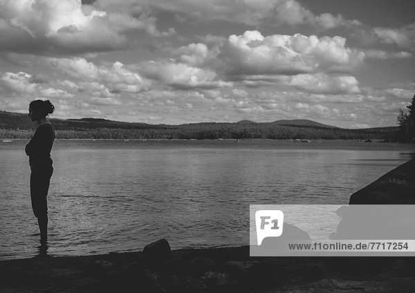 Woman standing in a lake with arms folded under dramatic skies Thetford mines quebec canada